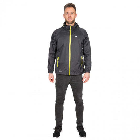 A person standing and wearing a black Trespass Qikpac waterproof jacket with yellow zipper details, paired with dark pants.