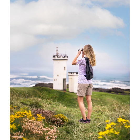 Woman wearing sling bag grey melange on a grassy hill

