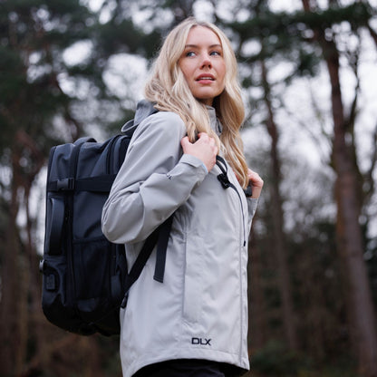 Woman in a gray jacket with a black backpack in a forest setting